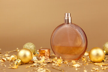 Unbranded round perfume bottle, gold christmas balls and paper firecracker pieces on golden...
