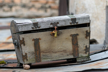Very old wooden chest with rusty metallic decorations and lock with keys