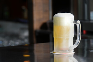 delicious mug of super cold and refreshing draft beer on the table in the blurred background