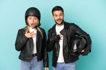 Couple with motorcycle helmet over isolated blue background surprised and shocked while looking right