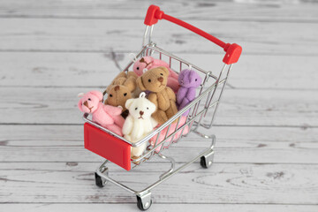 Many colorful toys teddy bears lie in the grocery cart. Shopping in the market. Buying gifts for...