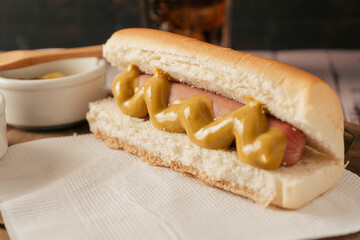 Close-up of a hotdog with mustard on a white paper napkin. Fast food concept.