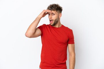 Fototapeta na wymiar Young caucasian handsome man isolated on white background doing surprise gesture while looking to the side