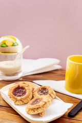 High view some homemade butter cookies with jam, in the background you can see a sugar bowl out of focus. Homemade and natural food concept. Vertical orientation. Copy space.