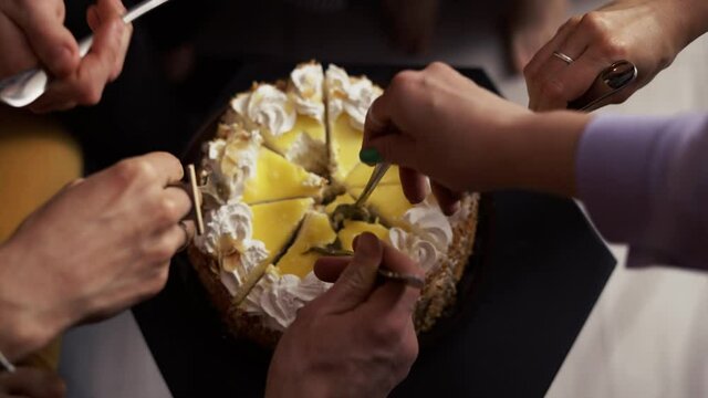 People grabbing cake slices using forks