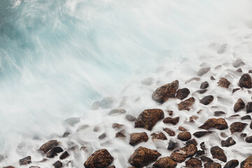 High angle view to stone beach. Sea waves on the motion. Tenerife, Canary Islands, Spain.