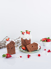 Easter cake made of chocolate dough, decorated with meringues and strawberries. Easter decor on white background 