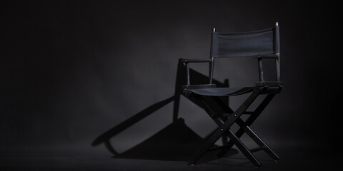 Black director chair is isolated on black background.it use in video production or movie industry.studio shot. - obrazy, fototapety, plakaty