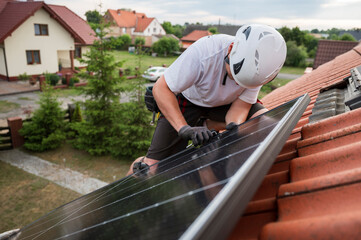 Engineer on the house roof assembles photovoltaic panel.