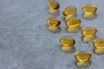 Omega 3 and fish oil capsules scattered on the grey marble