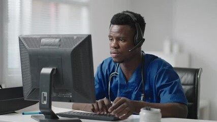Afro-american male doctor or nurse with headset and computer working at hospital .young professional therapist doctor consulting customer client using remote communication speaking on webcam
