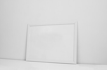 frame mockup hanging on the wall. minimalist interior design for mockup poster and print design. white wooden frame on white wall background.