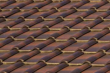 the roof is made of ceramic brown two-tone tiles, brightly lit by the sun's rays. background for design and desktop.