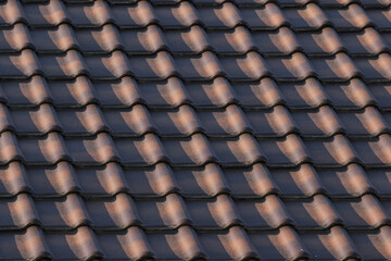 the roof is made of ceramic brown two-tone tiles in the rays of the setting sun and the shadow on it. background for design and desktop.