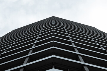Looking up shot of a business building. The structure is metallic with a monochromatic tone pointing towards a bright white sky. 