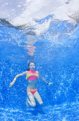Underwater image. Young girl jumps in the pool.