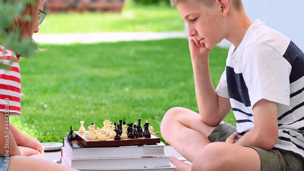 Wall mural brother and sister playing chess in the backyard with green lawn