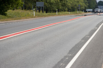 Asphalt road. Double lane road stripes  white and red. Selective focus