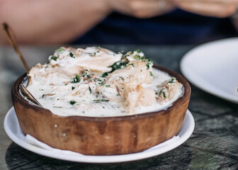 Man's hands in a restaurant having dinner with a traditional chicken dish in a creamy sauce. Soft focus
