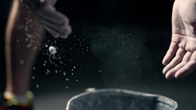 A athlete is rubbing magnesia on hands and clapping. Close up of male boxer hands with talcum powder. A man is preparing for a workout at the gym. Concept of lifestyle health and sports. Slow motion.