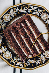Devil's Food chocolate layer cake on black white gold plate with gold fork