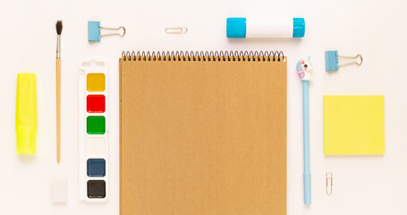 Top view of modern white, blue, yellow office desktop with school supplies and stationery on table around empty space for text. Back to school concept flat lay with mockup