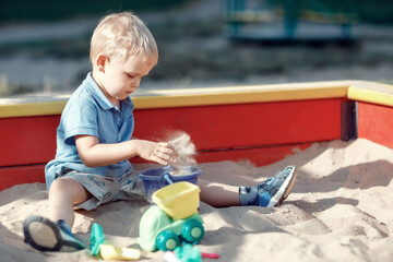 Small boy playing with sand toys in a sandbox