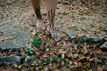 Feet with painted roots surrounded by roots in a park