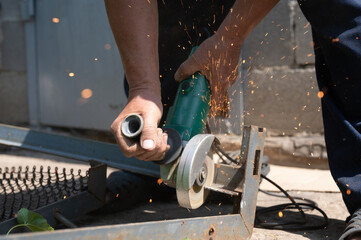Unrecognizable worker cutting metal using circular saw