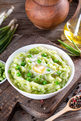 Delicate mashed potatoes with green peas, flavored with butter and spices on a table. Delicious homemade food