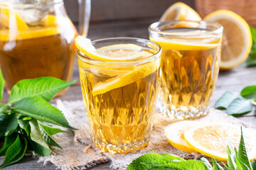 Refreshing drink, iced tea with lime wedges in glass on a wooden table. Summer drinks.