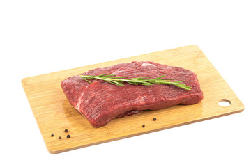 Raw beef on a cutting board with rosemary and peppercorns.