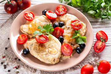 Fried chicken chop. Home fried chicken chop with tomatoes, olives and cheese on a wooden table. Rustic style.
