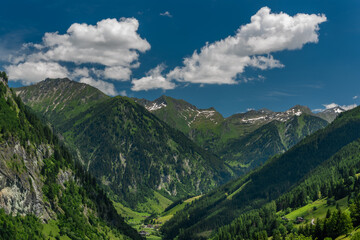 Fototapeta na wymiar Summer valley with Grossarler Ache small river and blue cloudy sky
