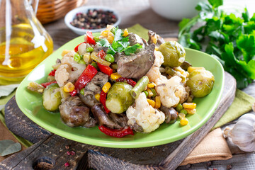 Stewed vegetables with chicken liver on wooden table. Healthy food.