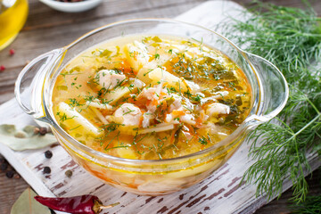 Chicken soup with pasta with carrots and green onions on table
