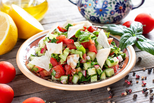 Vegetarian fattoush salad on table. Traditional Middle Eastern salad with toasted pita bread and vegetables. Lebanese cuisine.