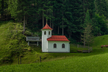 Fototapeta na wymiar Wolfaukapelle chapel in sunny cloudy morning in Austria mountains