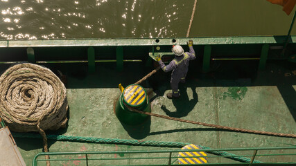 One seaman watching the mooring line during mooring of cargo ship - obrazy, fototapety, plakaty