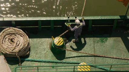 Fotobehang One seaman watching the mooring line during mooring of cargo ship © Genya