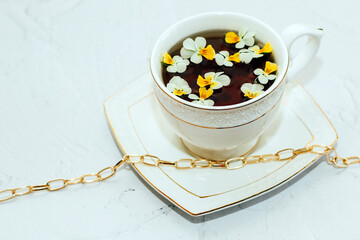 A beautiful white cup with a gold border, decorated with flowers and gold jewelry. Business account design.