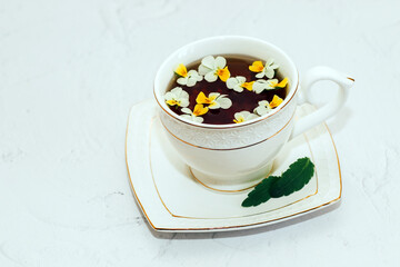 A beautiful white cup with a gold border decorated with flowers, herbal green healthy tea. Business account design.