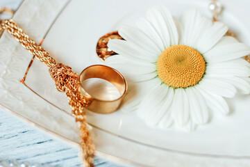 Delicate daisies close-up with gold jewelry. Chains, pendants, rings on a stand.