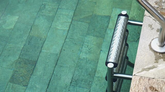 Swimming pool with metal ladder stair and gren water