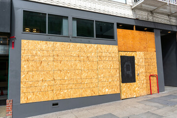 Exterior view of permanently closed business, store, restaurant boarded up with plywood sheets to...