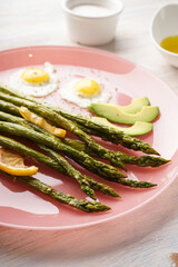 Stir-fried eggs with green asparagus in a plate on a wooden background. Close-up.