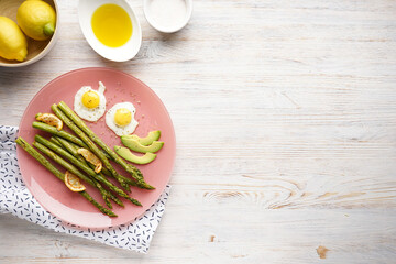 Stir-fried eggs with green asparagus in a plate on a wooden background, place for text. Top view.