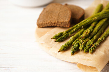 Baked asparagus on a wooden background, place for text.