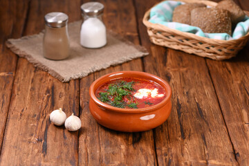 Obraz na płótnie Canvas Russian red soup borsch with sour cream and dill in clay plate.