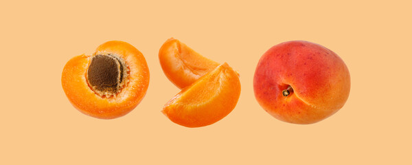 Fresh ripe whole, half and slices apricot fruits  isolated on  light orange
